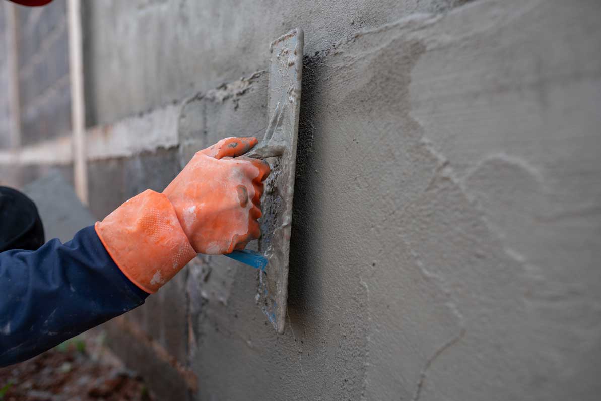 Contractor repairing a concrete block wall with a trowel